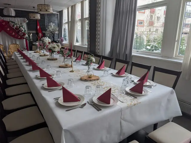 Daylight from tall windows across a long table of raspberry napkins, white hydrangeas and wood slices with gold tealight lanterns